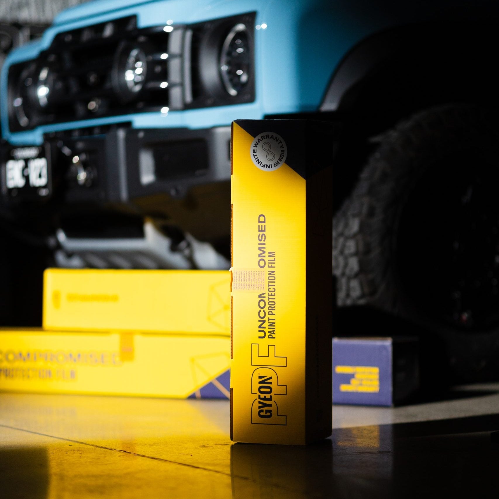 Close-up of a yellow tire pressure gauge with a blue vehicle in the background