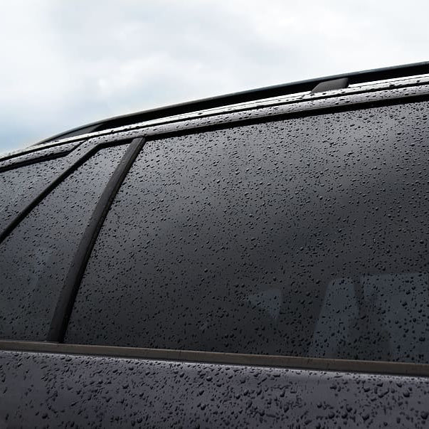 Raindrops on a tinted car window with a blurred background in Marietta