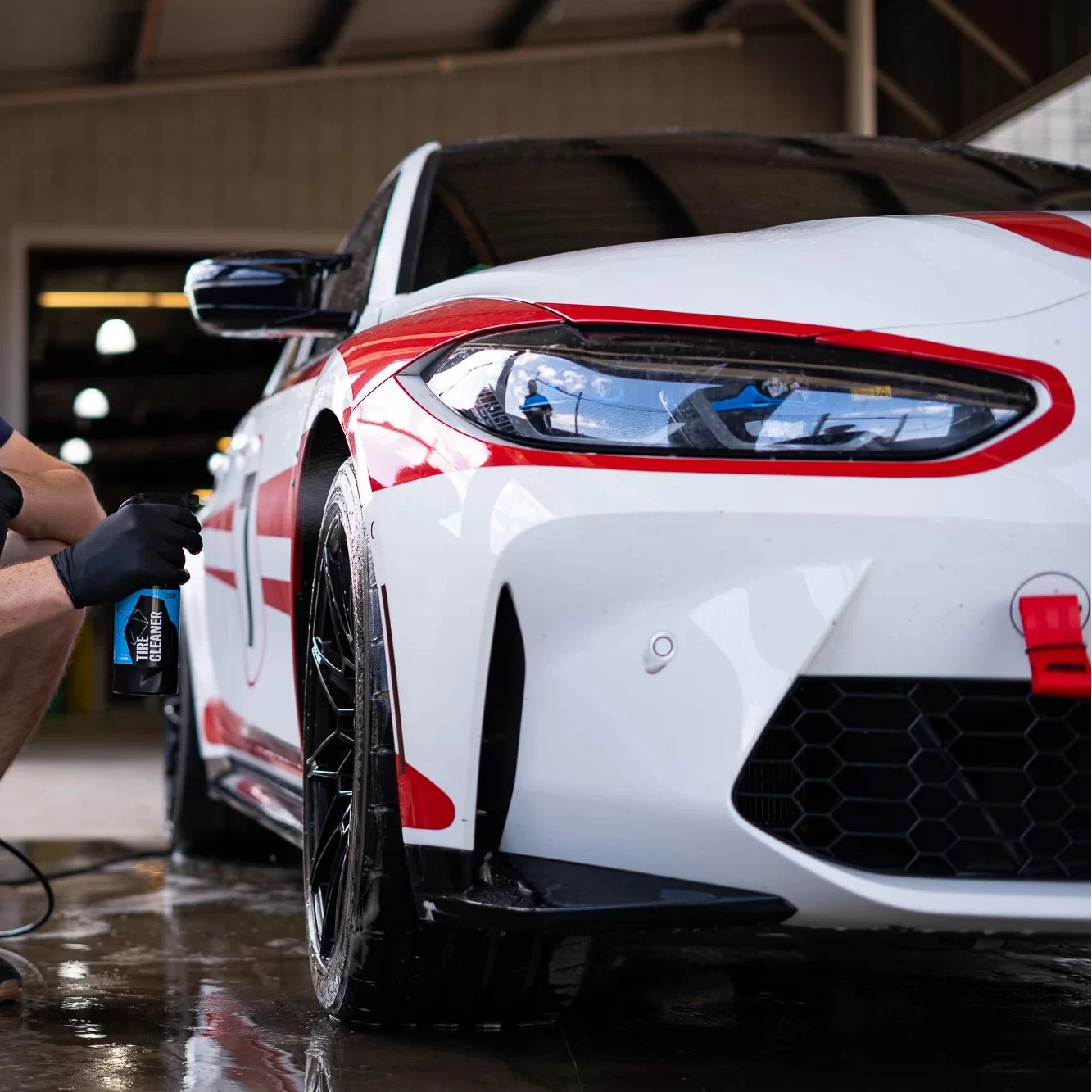 Person working on a white and red sports car in a garage.